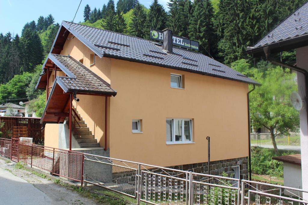 una pequeña casa amarilla con una valla delante en Hostel Srebrenica en Srebrenica