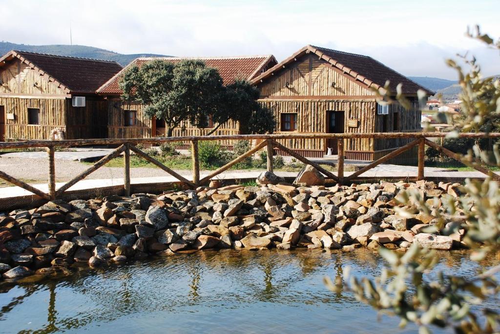 um grupo de edifícios de madeira ao lado de uma massa de água em El Rincon del Cerrillo em Cortijo de Arriba