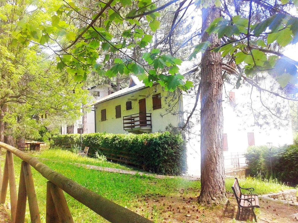 een wit huis met een hek en een boom bij Villaggio Barilari in Minucciano