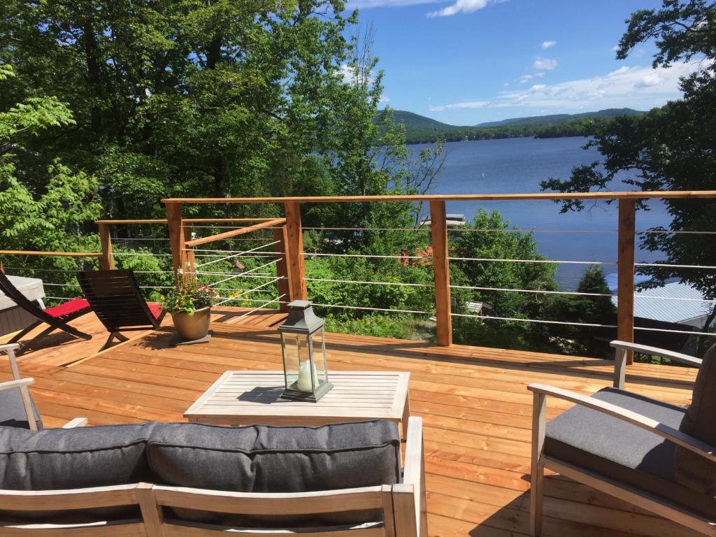 a deck with a couch and chairs and a table at Manoir du Lac Sept-Îles in Saint-Raymond