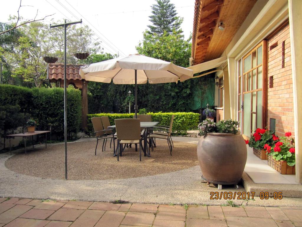 een patio met een parasol en een tafel en stoelen bij 'The Rose' Business Travelers in Yehud
