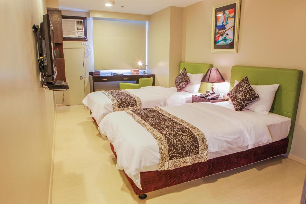 The Exchange Regency Residence Hotel Managed by HII في مانيلا: غرفه فندقيه سريرين وتلفزيون