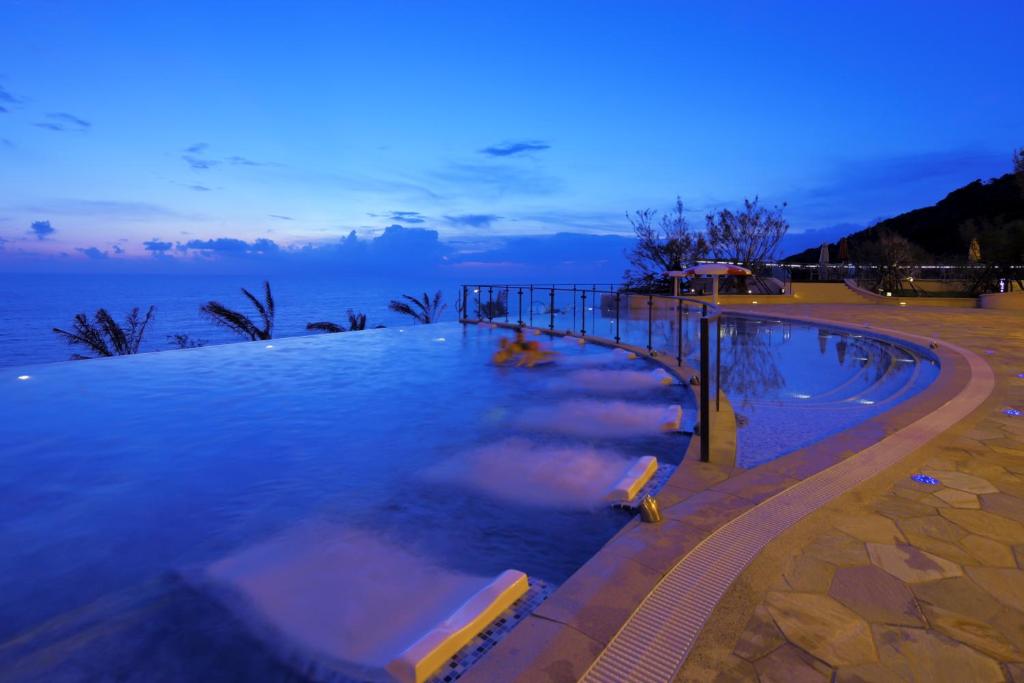 a large swimming pool next to the ocean at night at H Resort in Checheng