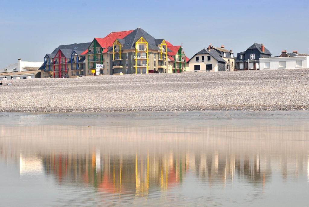 un grupo de casas se reflejan en el agua en Madame Vacances Les Terrasses De La Plage en Cayeux-sur-Mer