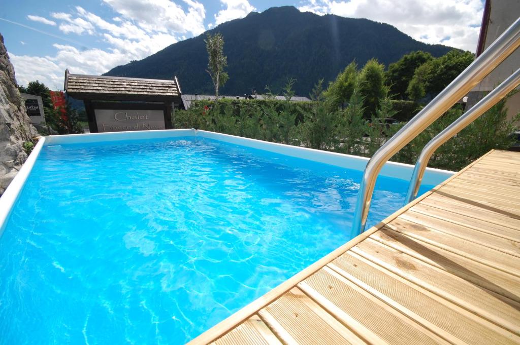 una grande piscina blu accanto a una terrazza in legno di Chalet Fiocco Di Neve a Pinzolo