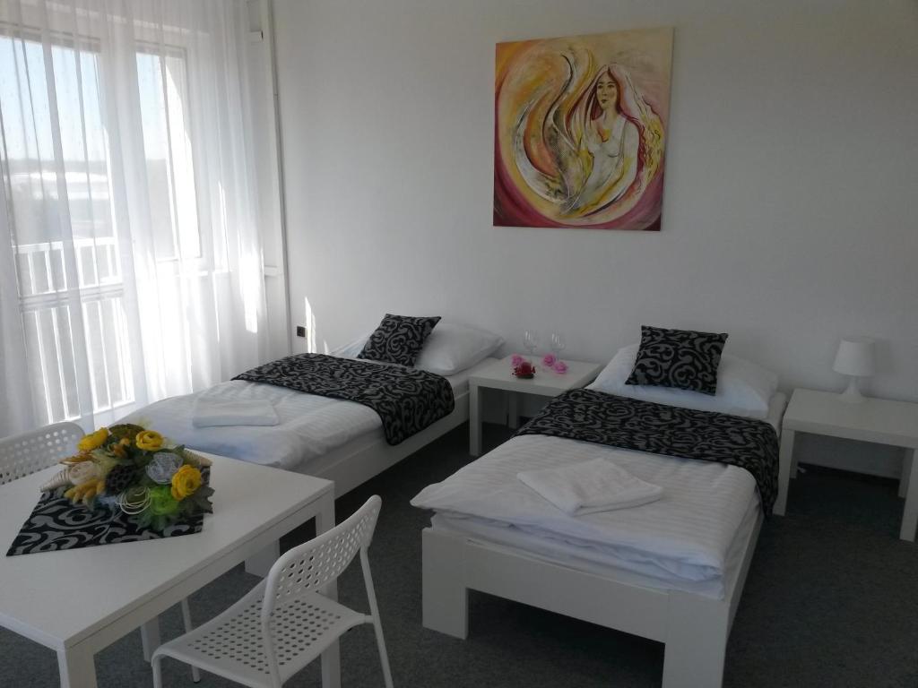 Cette chambre comprend 3 lits, une table et des chaises. dans l'établissement Ubytovna Kubra, à Hodonín