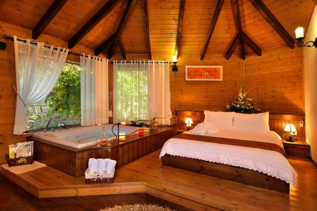 una camera con letto e vasca da bagno di Talia Cabin Guest & Spa a Rosh Pinna