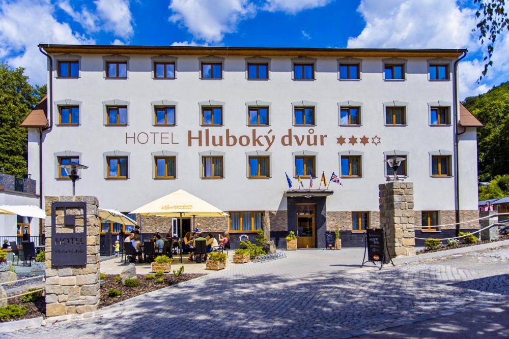 ein großes weißes Gebäude mit hotelorthologischem Antrieb in der Unterkunft Wellness Hotel Hluboký Dvůr in Hrubá Voda