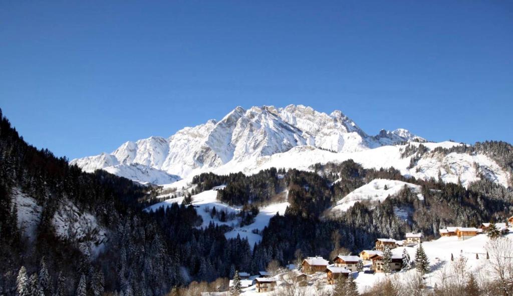 a snow covered mountain with a village in the foreground at 65m2 - balcon et vue sur les Aravis in La Giettaz