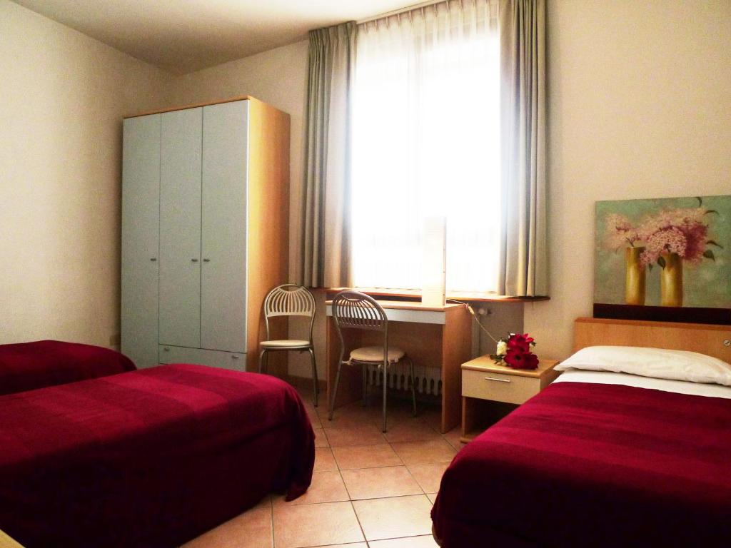 una camera d'albergo con 2 letti e una scrivania di Girasole House a Firenze