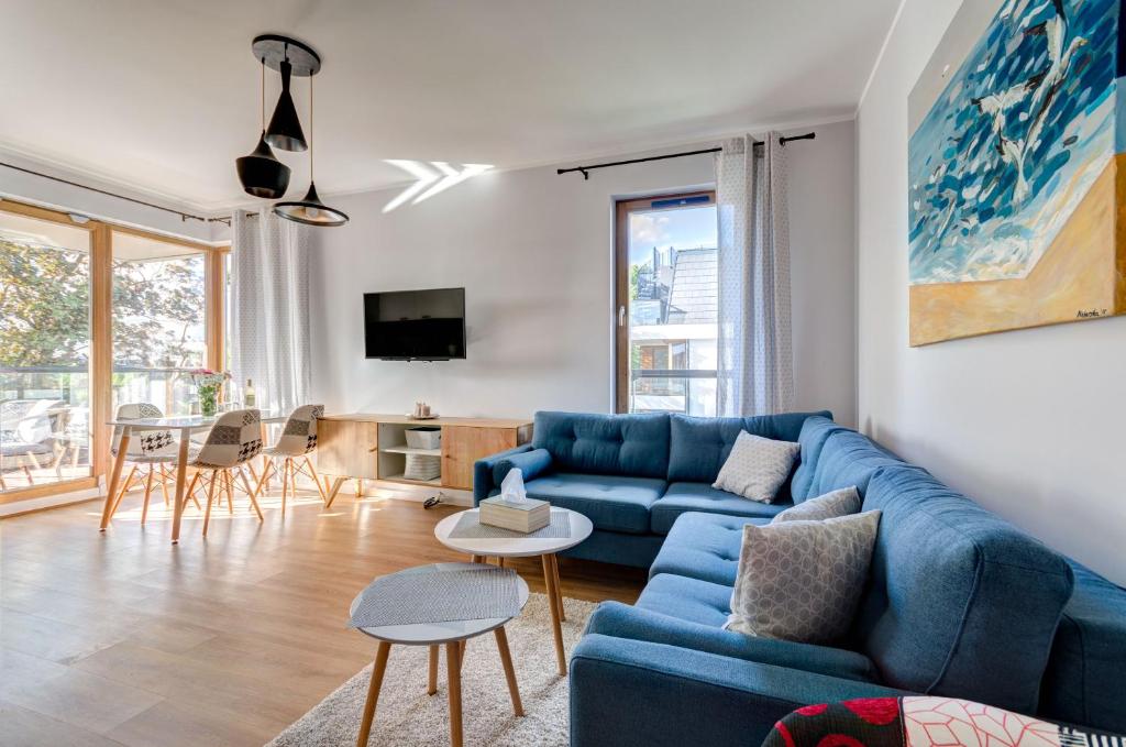 un soggiorno con divano blu e tavolo di Amber Baltic Apartment a Danzica