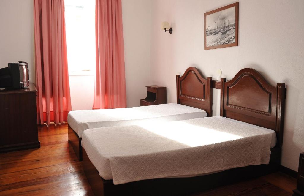 2 Betten in einem Hotelzimmer mit Fenster in der Unterkunft Hotel São Francisco in Horta