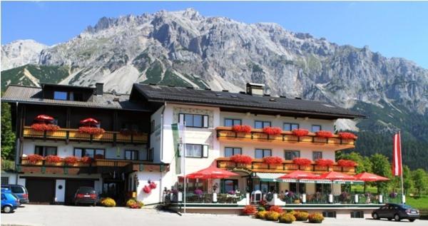 un edificio con ombrelloni rossi di fronte a una montagna di Der Brückenhof Ramsau a Ramsau am Dachstein