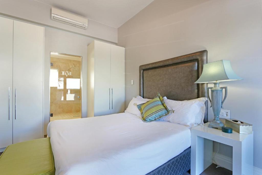 a bedroom with a large white bed with a lamp at Vetho Villa in Cape Town