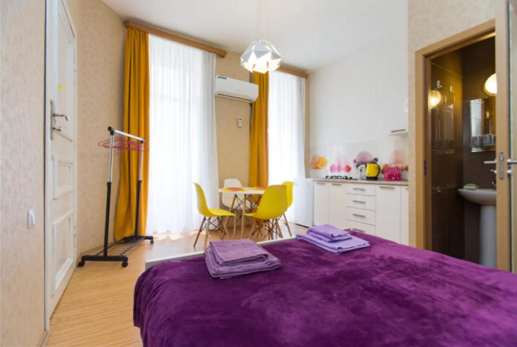 - une chambre avec un lit violet et une table avec des chaises dans l'établissement Pop Art Studio Apartment, à Tbilissi