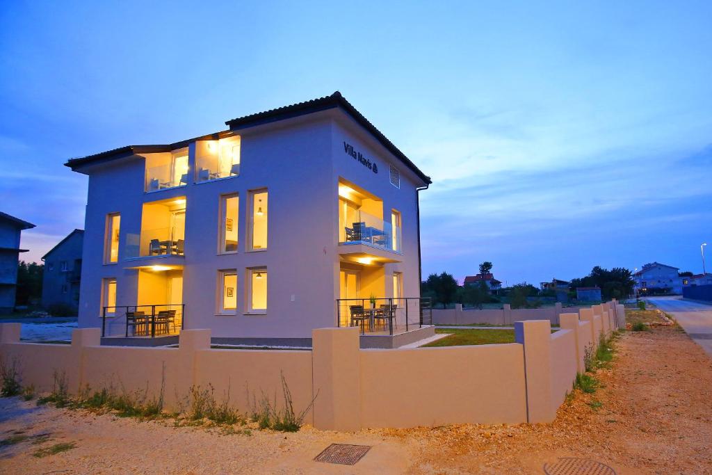 ein weißes Haus mit einem Zaun davor in der Unterkunft Apartments Villa Navi in Bibinje