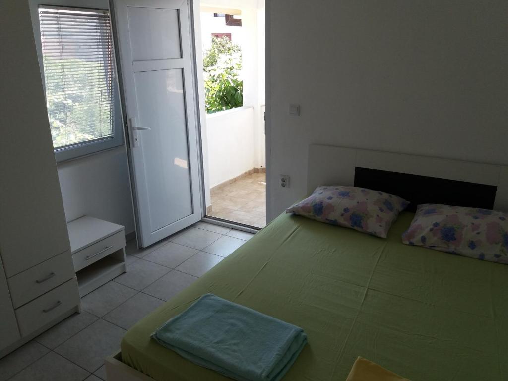 a bedroom with a green bed and a large window at Apartmani na moru in Bar