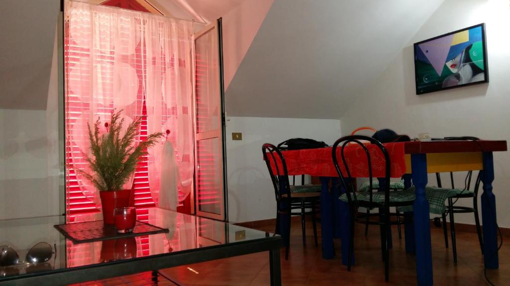 una sala da pranzo con tavolo e sedie rossi e una finestra di Grazioso appartamento con vista Reggia di Caserta a San Nicola La Strada