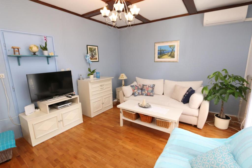 a living room with a white couch and a tv at Apartment Pijer in Novalja