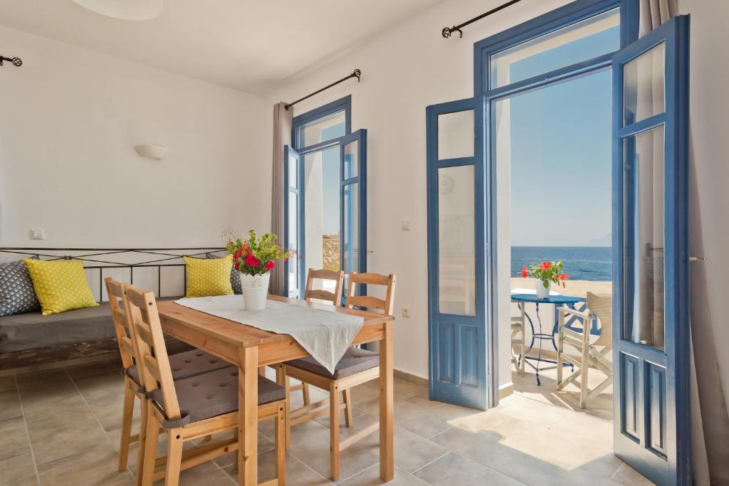 a dining room with a table and chairs with a view of the ocean at Alisachni Villas in Lefkos Karpathou