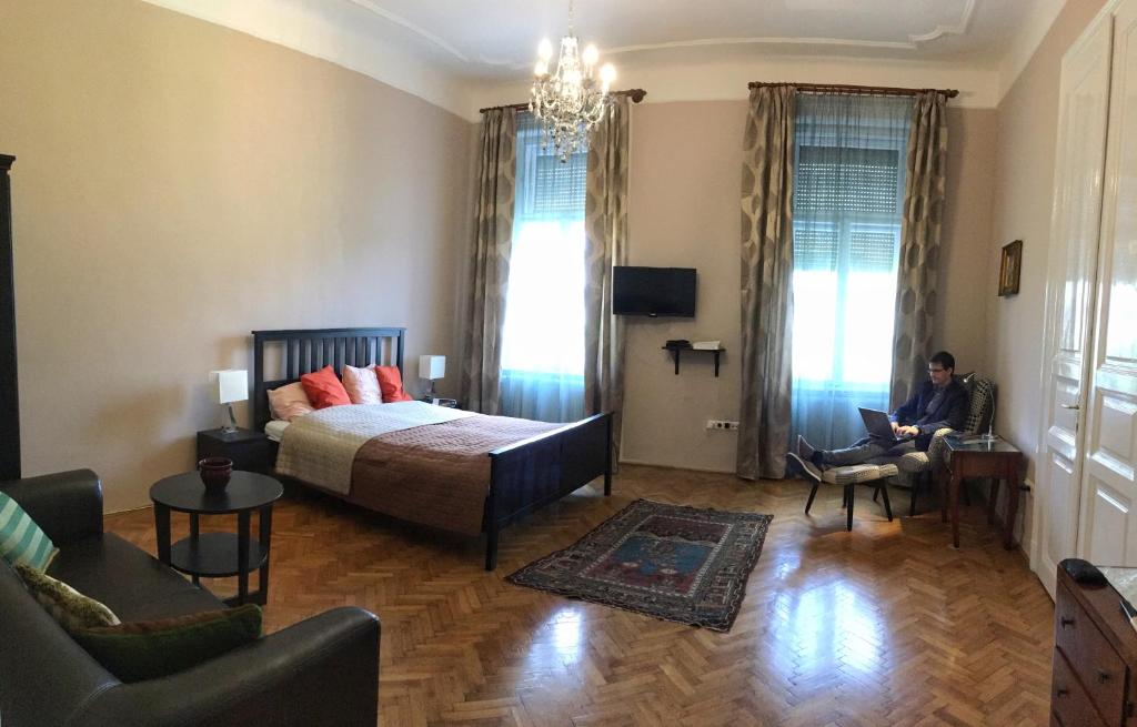 um quarto com uma cama e uma pessoa sentada numa cadeira em Diamonds Apartment with 2 rooms near Guzsdu udvar em Budapeste