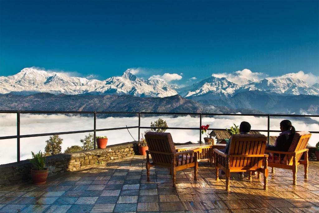 Dos personas sentadas en una mesa con vistas a las montañas en Raniban Retreat, en Pokhara