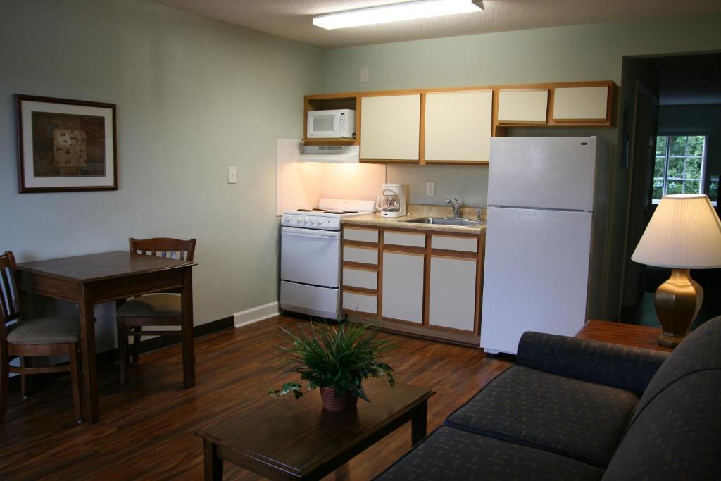 a kitchen and living room with a table and a refrigerator at Affordable Suites Jacksonville in Jacksonville