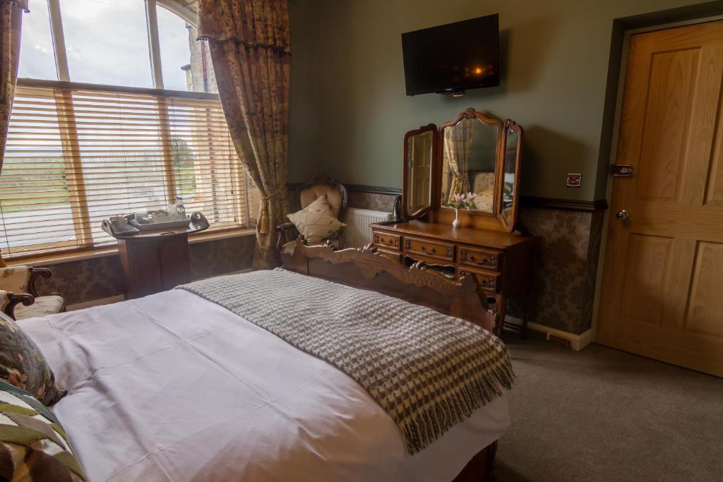 a bedroom with a bed and a mirror and a dresser at The Red Pump Inn in Clitheroe