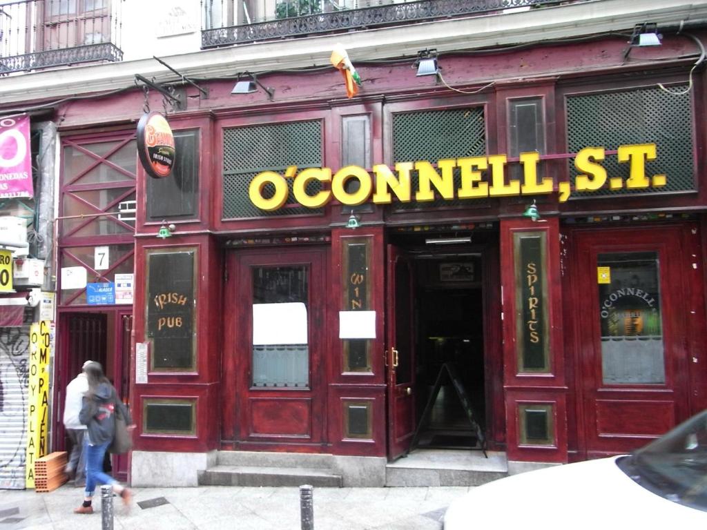 a woman walking in front of a red building at Alojamiento Temporal Corazón Madrid in Madrid