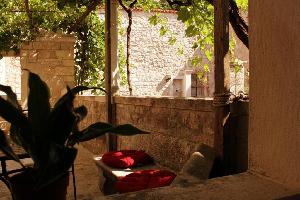 a room with a bench with red pillows and a plant at Vacation house "Kaštil" Pučišća - Brač in Pučišća