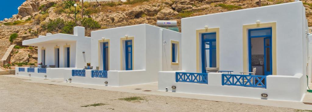 a row of white buildings with blue doors on a hill at Alisachni Villas in Lefkos Karpathou