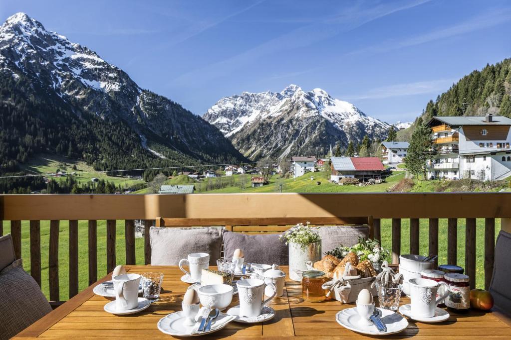 una mesa en un balcón con vistas a las montañas en Ahorn Chalet Mittelberg, en Mittelberg