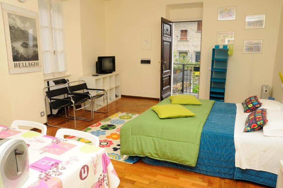 a room with two beds and a table and a television at Appartamenti I Giardini Di Villa Melzi in Bellagio