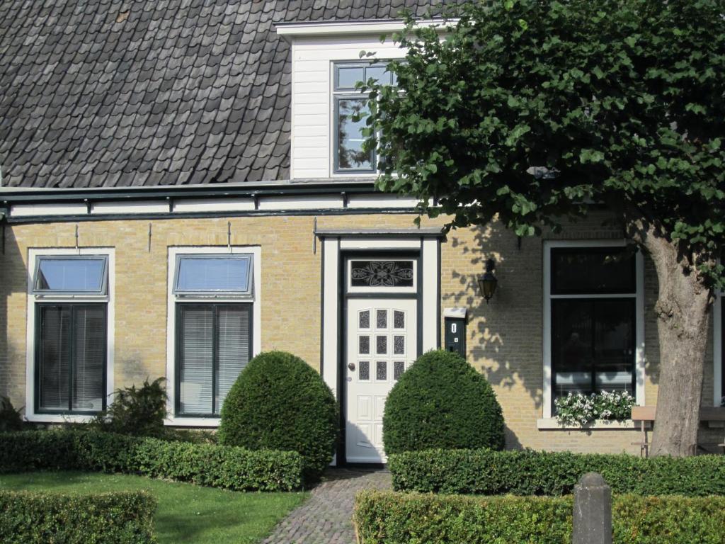 una casa con una puerta blanca y arbustos en B&B De Gouden Vlo en Donkerbroek