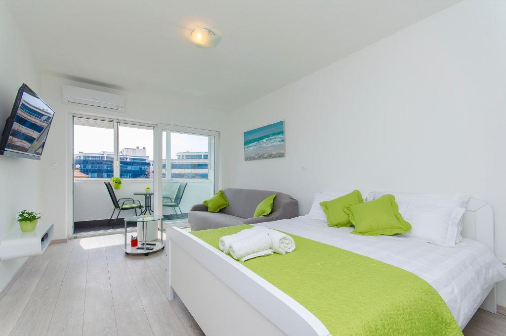 a white bedroom with a large bed with green pillows at Super amazing apartments in Split