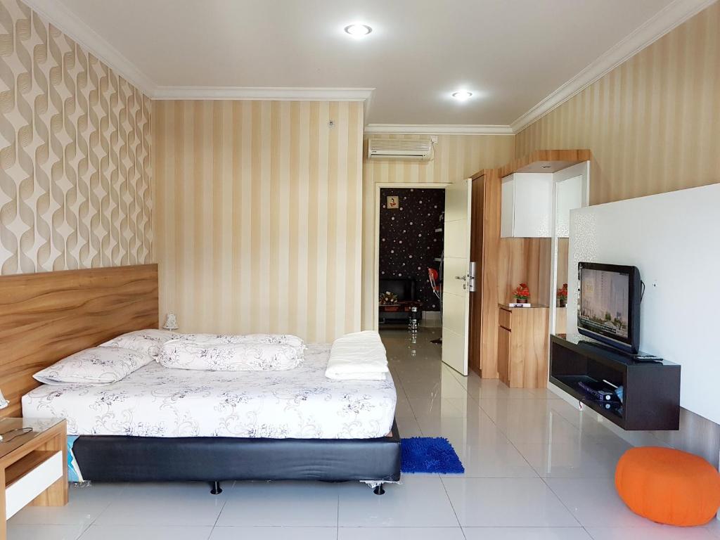 een slaapkamer met een bed en een flatscreen-tv bij Apartemen MTC 623 in Manado