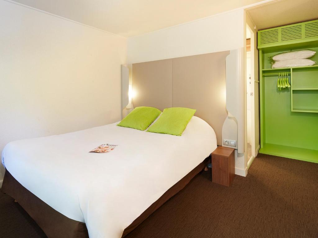 a bedroom with a large white bed with green accents at Campanile Orleans - La Source in Orléans