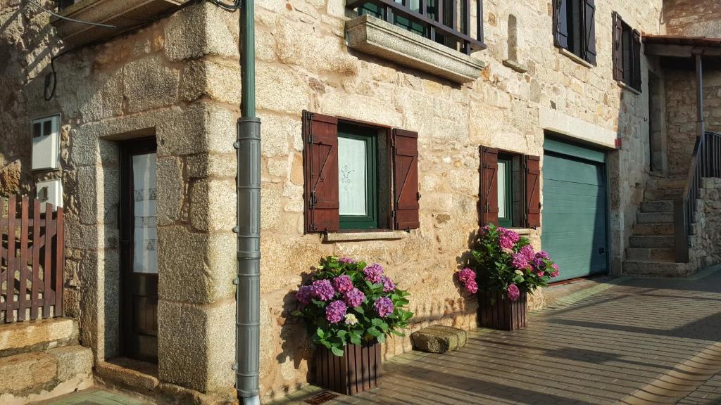 un edificio con dos ventanas con flores. en Casa do patín, en Palmeira