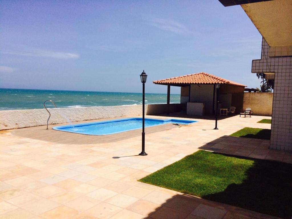 a swimming pool next to a beach with the ocean at Casa em Condomínio Barra São Miguel in Barra de São Miguel