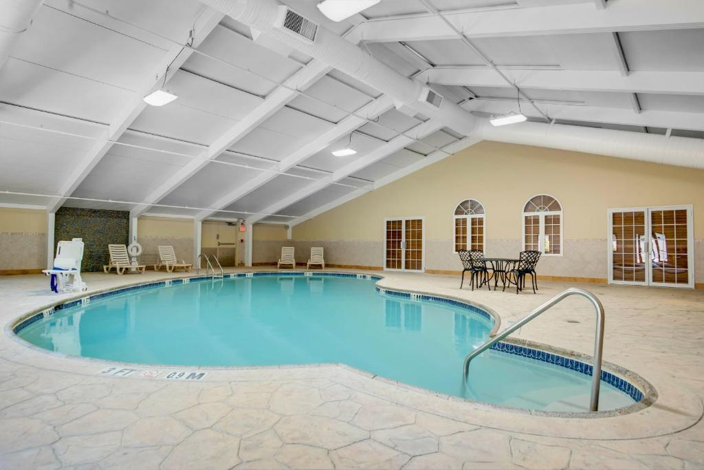 uma grande piscina numa grande sala com mesas e cadeiras em Days Hotel by Wyndham Toms River Jersey Shore em Toms River