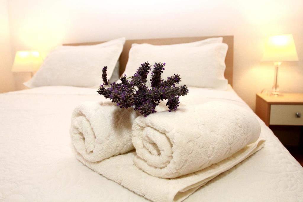 een bed met witte handdoeken en een boeket bloemen bij Apartmani Murtilica in Trogir