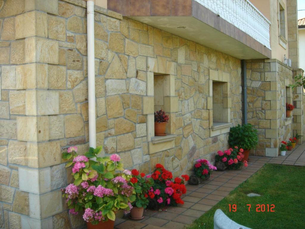 un edificio de piedra con flores delante en Residencial Santamaría, en Sancibrián