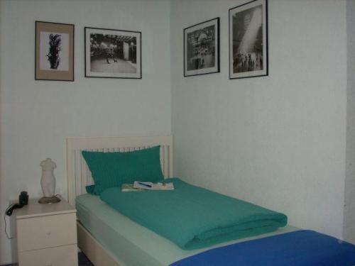 a bedroom with a green bed with pictures on the wall at Hotel zur Eiche in Oberthal