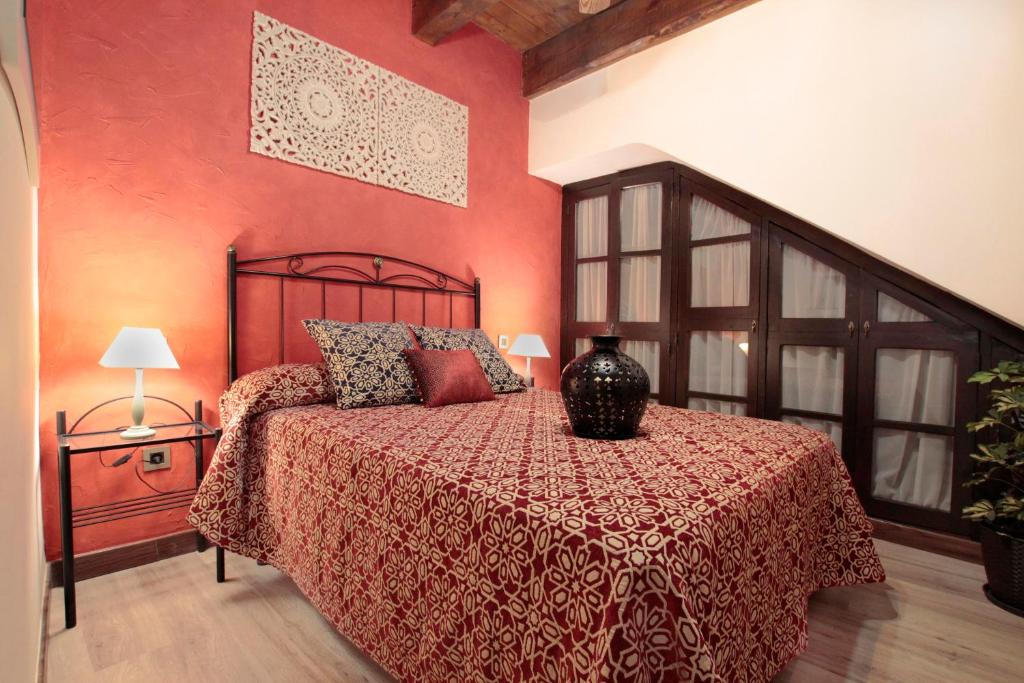 a bedroom with a bed with a red wall at Apartamentos Alcantara in Toledo