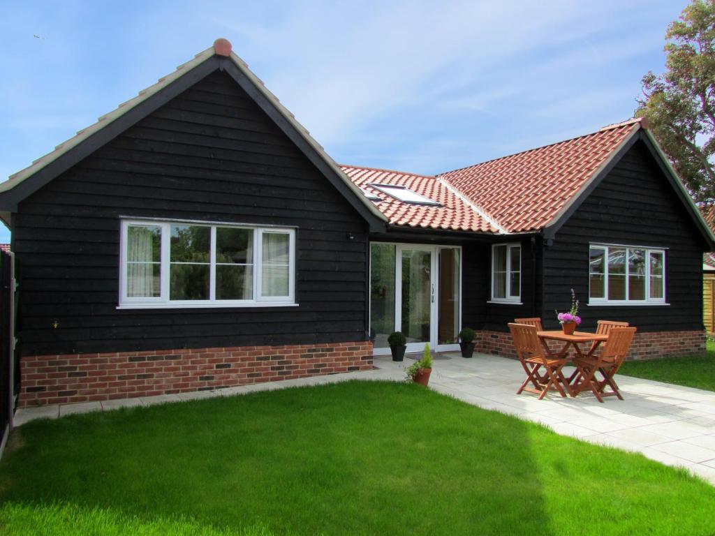 ein schwarzes Haus mit rotem Dach in der Unterkunft 2 Suffolk Cottage, Knodishall in Aldringham