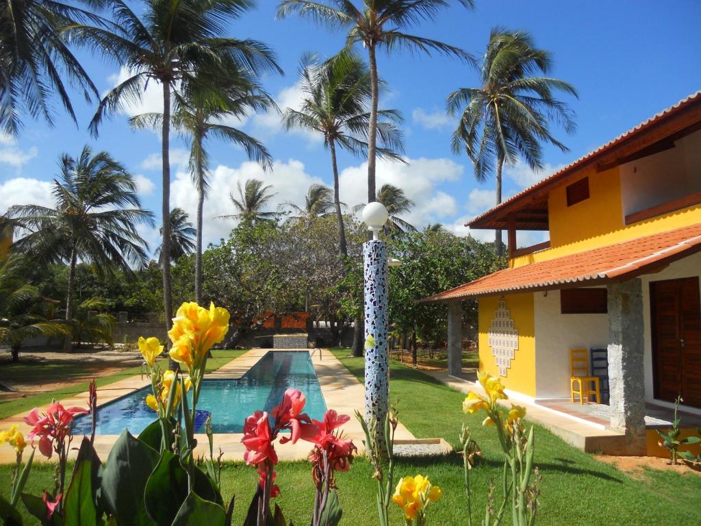 un complejo con piscina y palmeras en Pousada Temperança en Beberibe