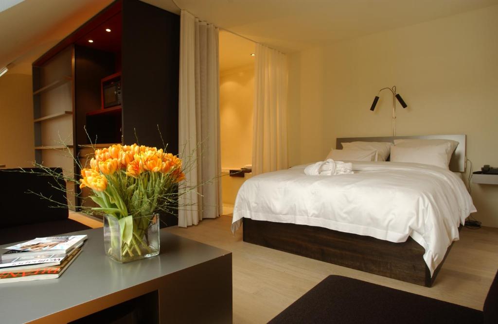 a bedroom with a bed and a table with a vase of flowers at Sorell Hotel Rigiblick - Studios & Spa Suites in Zürich