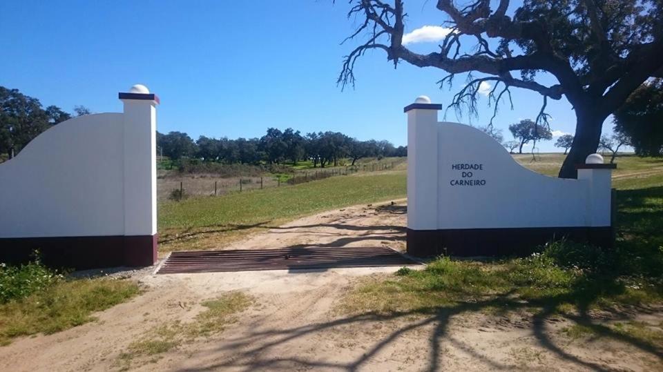 a gate on a dirt road next to a tree at Agro-Turismo Herdade do Carneiro in Escoural