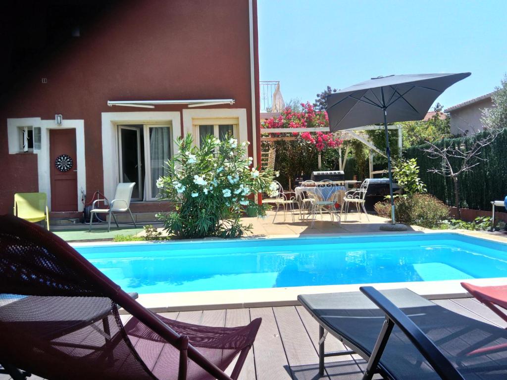 einen Pool mit Stühlen und einem Sonnenschirm neben einem Haus in der Unterkunft Chambres d'Hôtes de la Grone in Argelès-sur-Mer