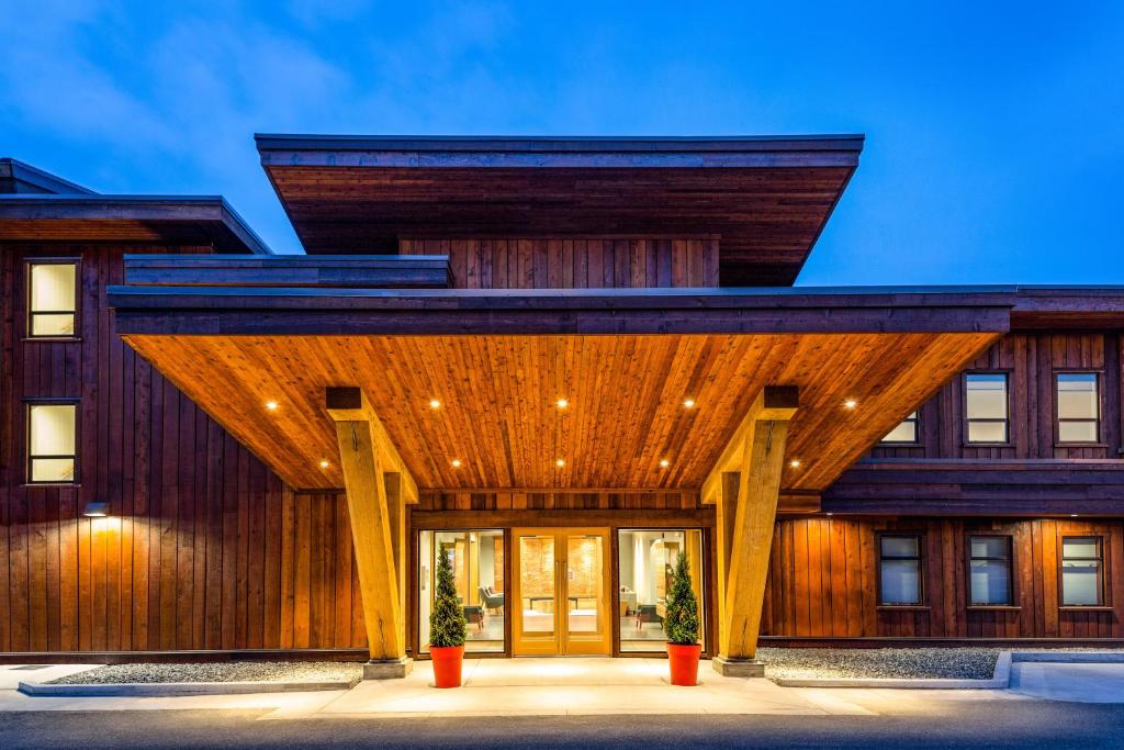 a house with a wooden facade with two potted plants at Kwa'lilas Hotel in Port Hardy